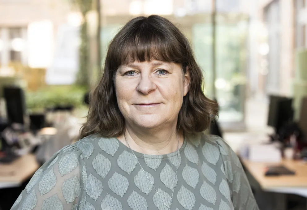 Porträtt av en kvinna med mellanmörkt hår och grön topp